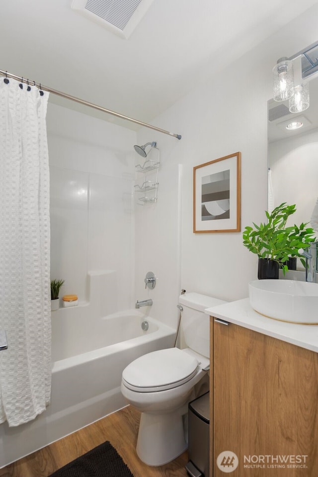 bathroom featuring visible vents, toilet, shower / bath combo, wood finished floors, and vanity