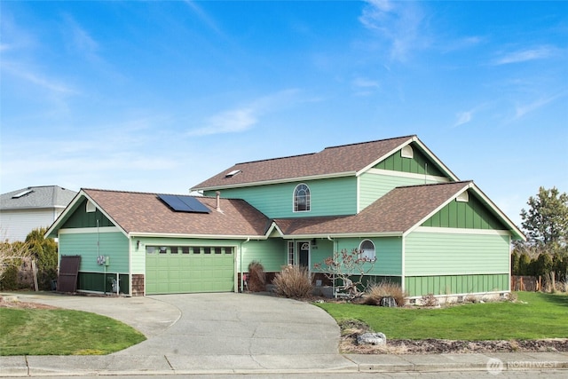 view of front facade featuring a front yard, driveway, roof with shingles, solar panels, and an attached garage