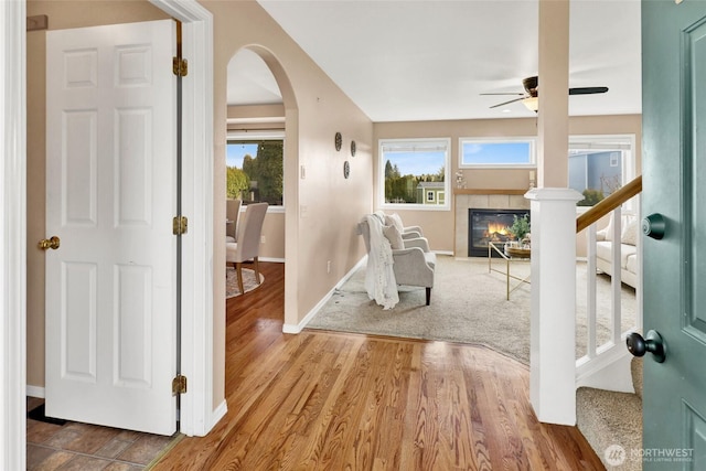 interior space featuring ceiling fan, wood finished floors, a healthy amount of sunlight, and a tile fireplace