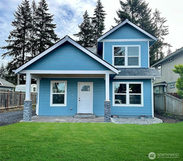 view of front of home with a front yard, fence, and a shingled roof