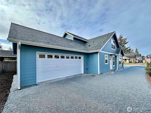 view of side of home with fence, a garage, and driveway