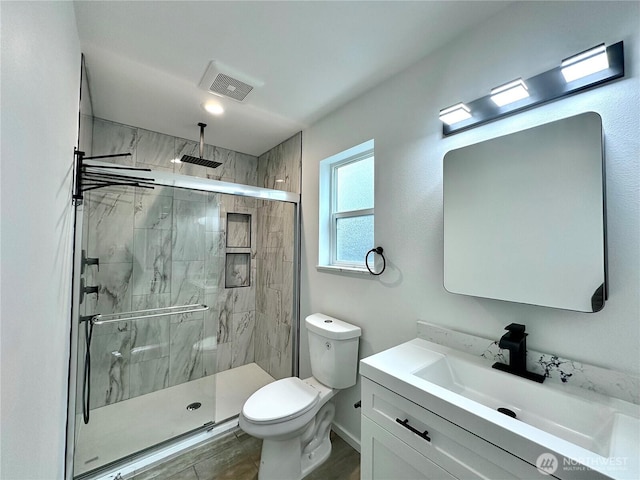 bathroom with vanity, toilet, visible vents, and a stall shower