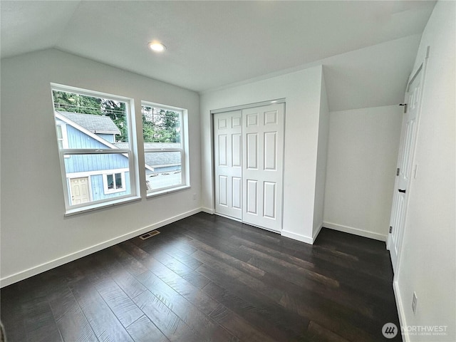 unfurnished bedroom featuring dark wood-style flooring, baseboards, and vaulted ceiling