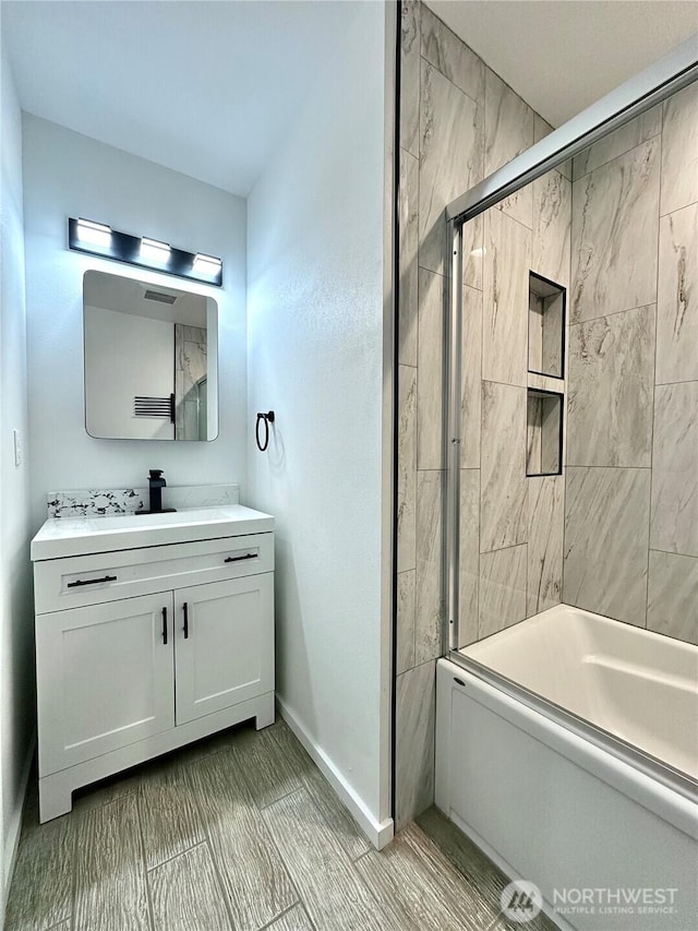 full bathroom with combined bath / shower with glass door, baseboards, and vanity