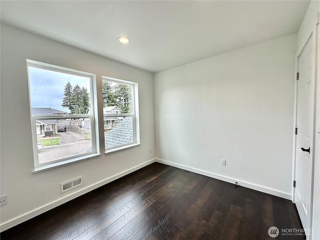 spare room with dark wood-type flooring, baseboards, and visible vents