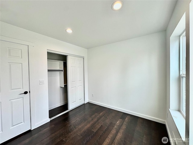 unfurnished bedroom featuring recessed lighting, a closet, baseboards, and dark wood finished floors