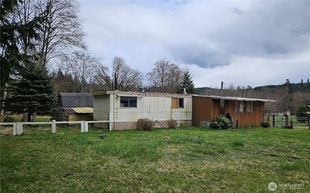 view of side of home with a lawn and fence