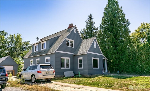 view of front of property with a chimney, a front yard, and roof with shingles