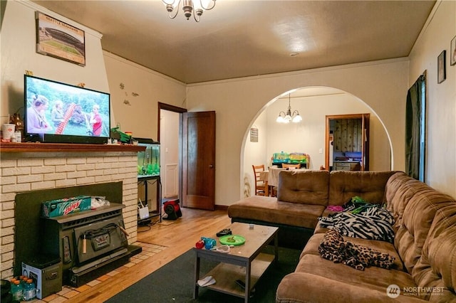 living room with a chandelier, arched walkways, a fireplace, and wood finished floors