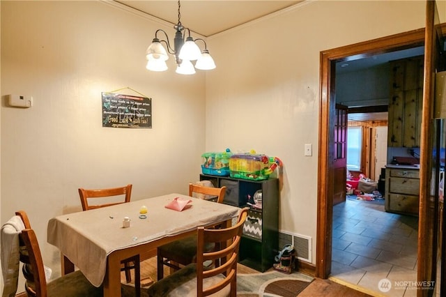 tiled dining room featuring a chandelier, visible vents, and crown molding