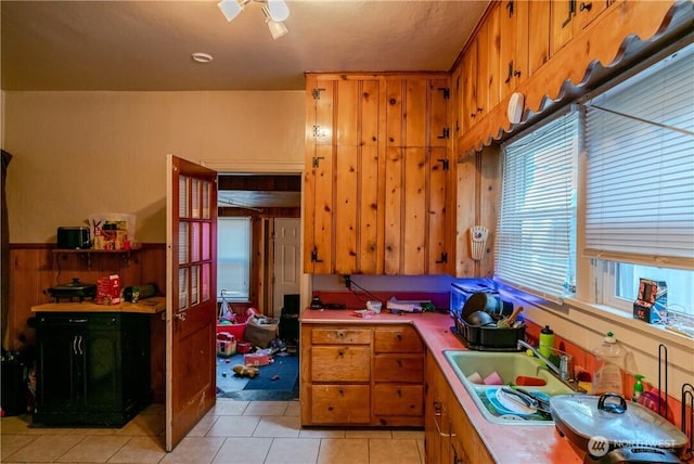 kitchen featuring light countertops, light tile patterned floors, brown cabinets, and a sink