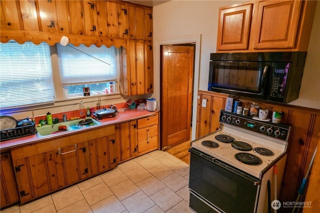 kitchen with brown cabinetry, white range with electric cooktop, a sink, light countertops, and black microwave