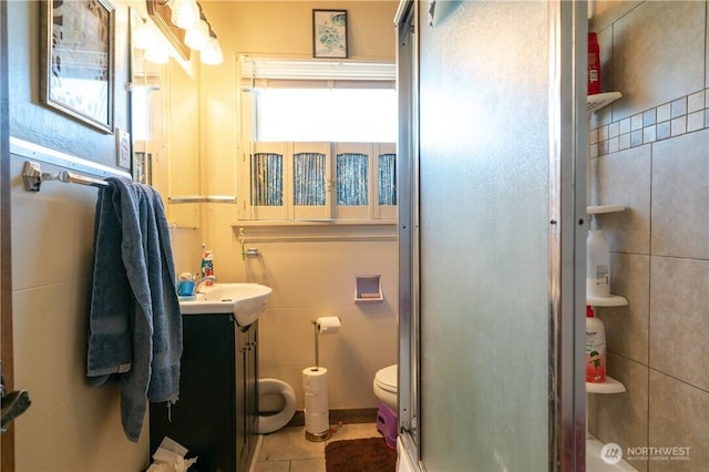 full bath with vanity, tile patterned flooring, a shower stall, tile walls, and toilet