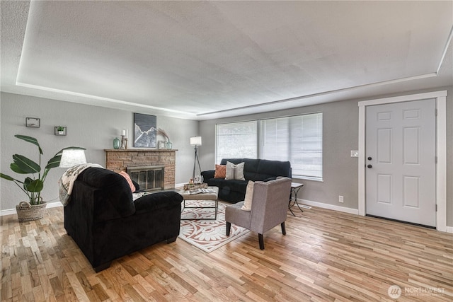 living area with baseboards, light wood-style floors, a fireplace, and a textured ceiling