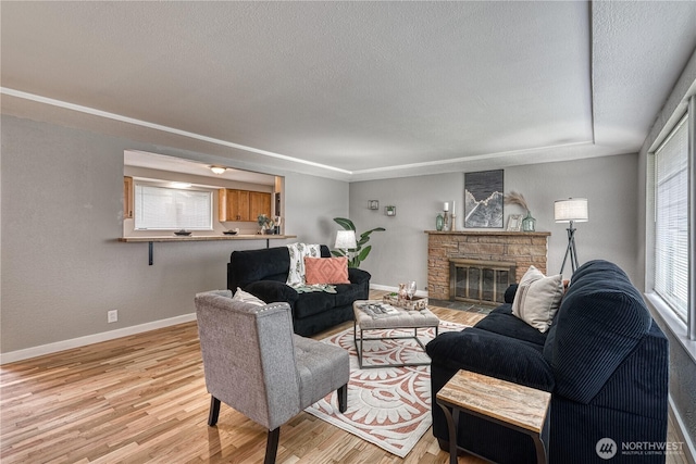 living room with light wood-style floors, baseboards, and a textured ceiling