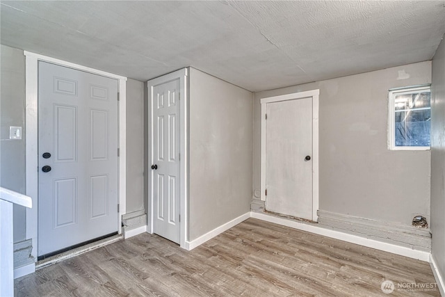 entryway featuring wood finished floors, baseboards, and a textured ceiling