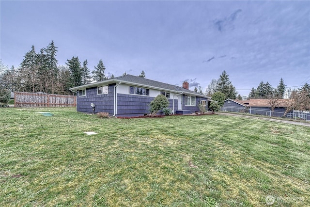 exterior space featuring a chimney, a front yard, and fence