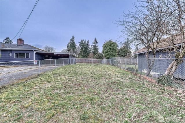 view of yard with an attached carport, driveway, and fence