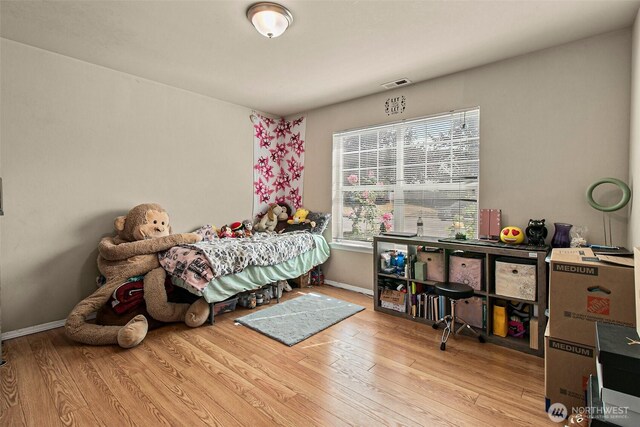 bedroom with visible vents, baseboards, and wood finished floors