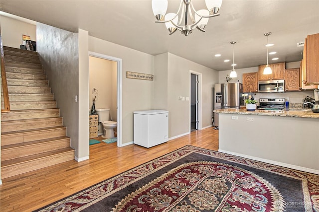 kitchen featuring pendant lighting, light wood-type flooring, appliances with stainless steel finishes, and a chandelier