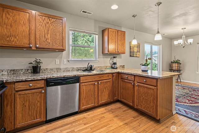 kitchen with visible vents, brown cabinets, a sink, a peninsula, and dishwasher