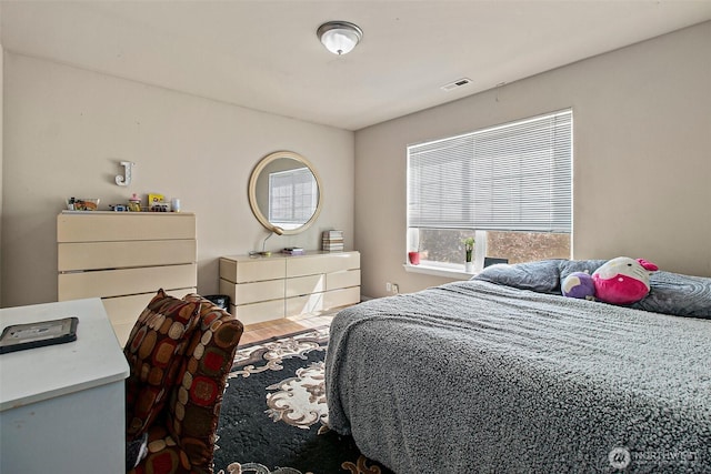 bedroom featuring wood finished floors and visible vents