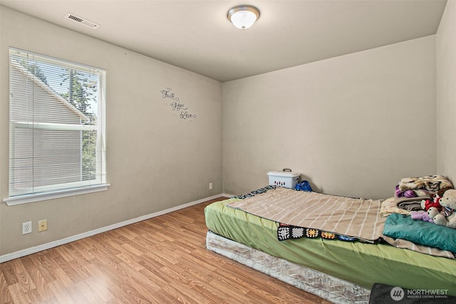 bedroom with wood finished floors, visible vents, and baseboards