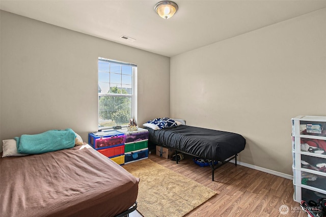 bedroom featuring baseboards, visible vents, and light wood finished floors