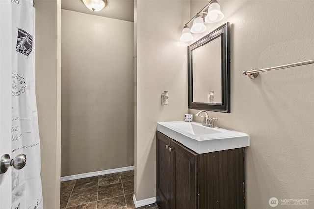 full bath featuring baseboards and vanity