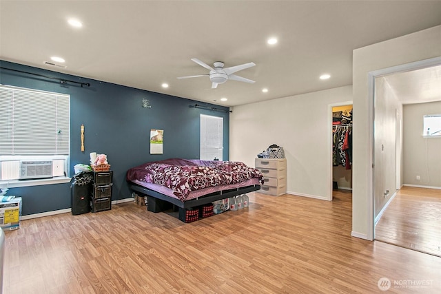 bedroom featuring cooling unit, baseboards, light wood-style flooring, recessed lighting, and a walk in closet