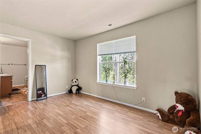 unfurnished bedroom with light wood-style flooring, baseboards, visible vents, and connected bathroom