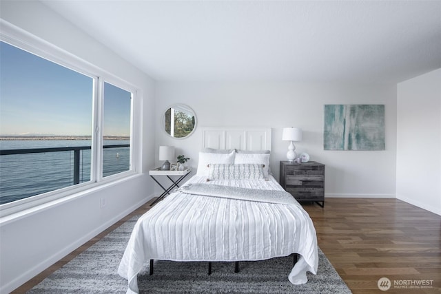 bedroom featuring baseboards, wood finished floors, and a water view