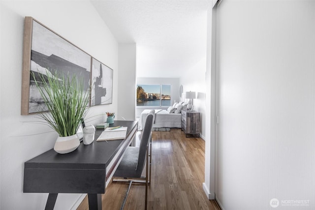 hallway featuring a textured ceiling, baseboards, and wood finished floors