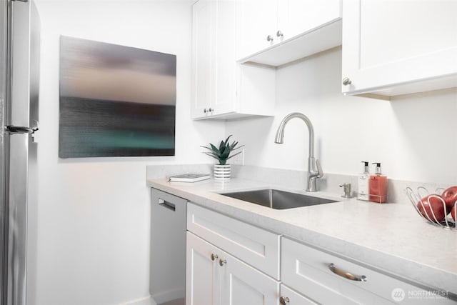 kitchen featuring white cabinetry, light stone countertops, stainless steel appliances, and a sink