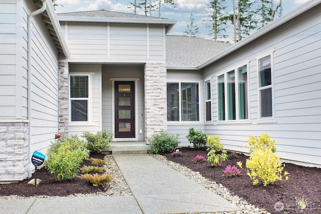 view of exterior entry with a shingled roof