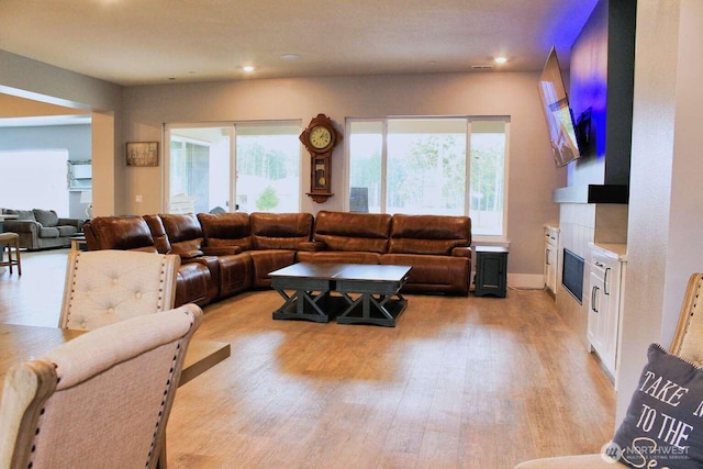 living room featuring recessed lighting, light wood-style flooring, and a large fireplace