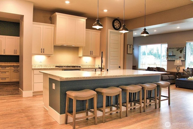 kitchen with light wood-style flooring, stainless steel gas stovetop, open floor plan, and light countertops