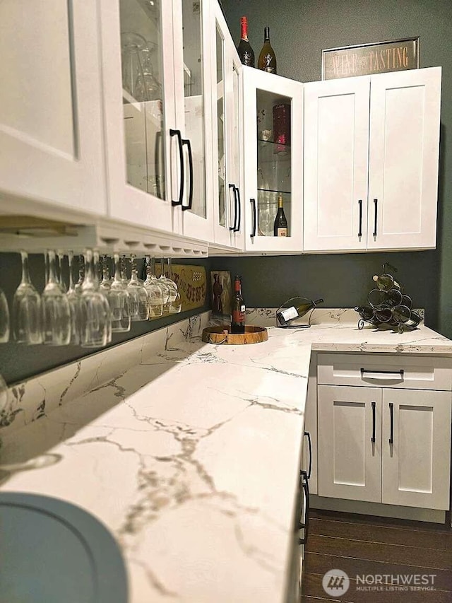 kitchen with light stone counters, white cabinets, and glass insert cabinets