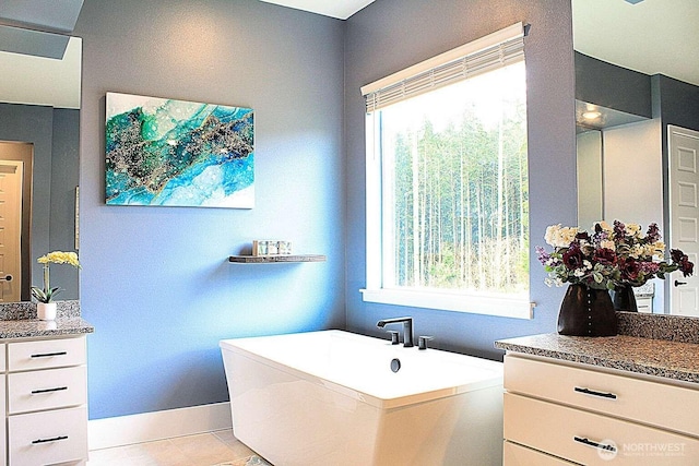 full bathroom featuring tile patterned flooring, a freestanding tub, vanity, and baseboards