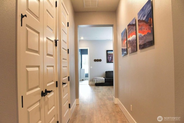 corridor with visible vents, baseboards, and light wood-style floors