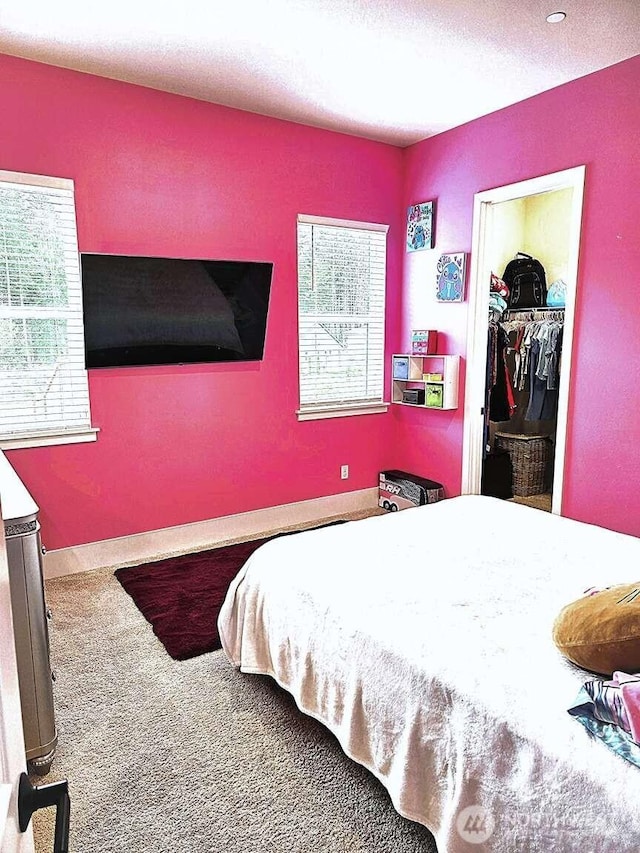 bedroom with a walk in closet, carpet flooring, and a textured ceiling