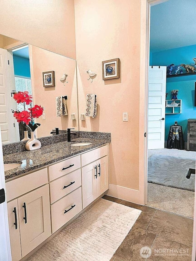 bathroom featuring double vanity, baseboards, and a sink