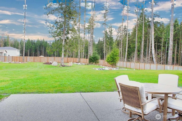 view of yard featuring outdoor dining space, a patio area, a view of trees, and fence private yard