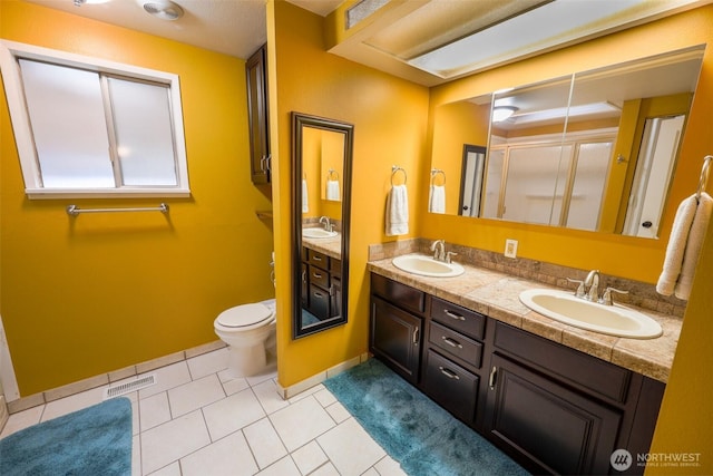 full bathroom with double vanity, toilet, tile patterned floors, and a sink