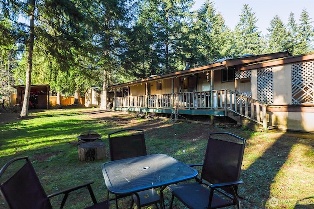 rear view of house with a fire pit, a lawn, an outbuilding, and a storage shed