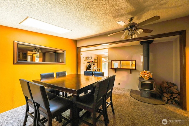 carpeted dining room with a ceiling fan, a wood stove, and a textured ceiling