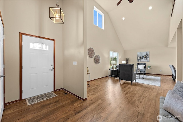 foyer entrance featuring baseboards, high vaulted ceiling, hardwood / wood-style floors, and a ceiling fan