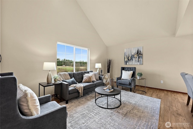 living room with baseboards, high vaulted ceiling, and wood finished floors