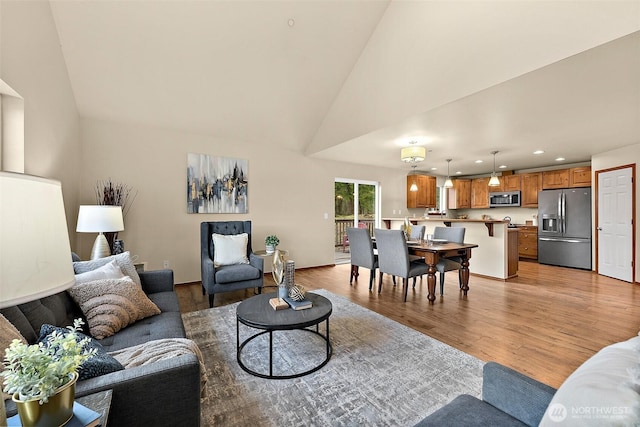 living room featuring recessed lighting, light wood-style floors, and high vaulted ceiling