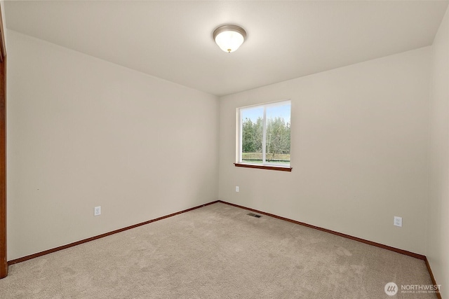 spare room featuring visible vents, light carpet, and baseboards